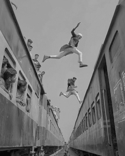 A person leaping between the roofs of two moving trains